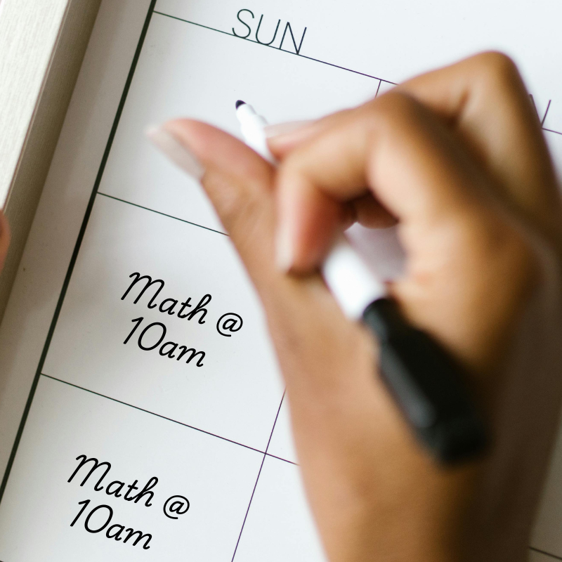 Photo of a womam writing math tutoring at 10am on her calendar every Sunday. Original phone by RDNE Stock project: https://www.pexels.com/photo/woman-writing-in-calendar-8581118/. Edited to add text 'Math at 10am' on Sundays.